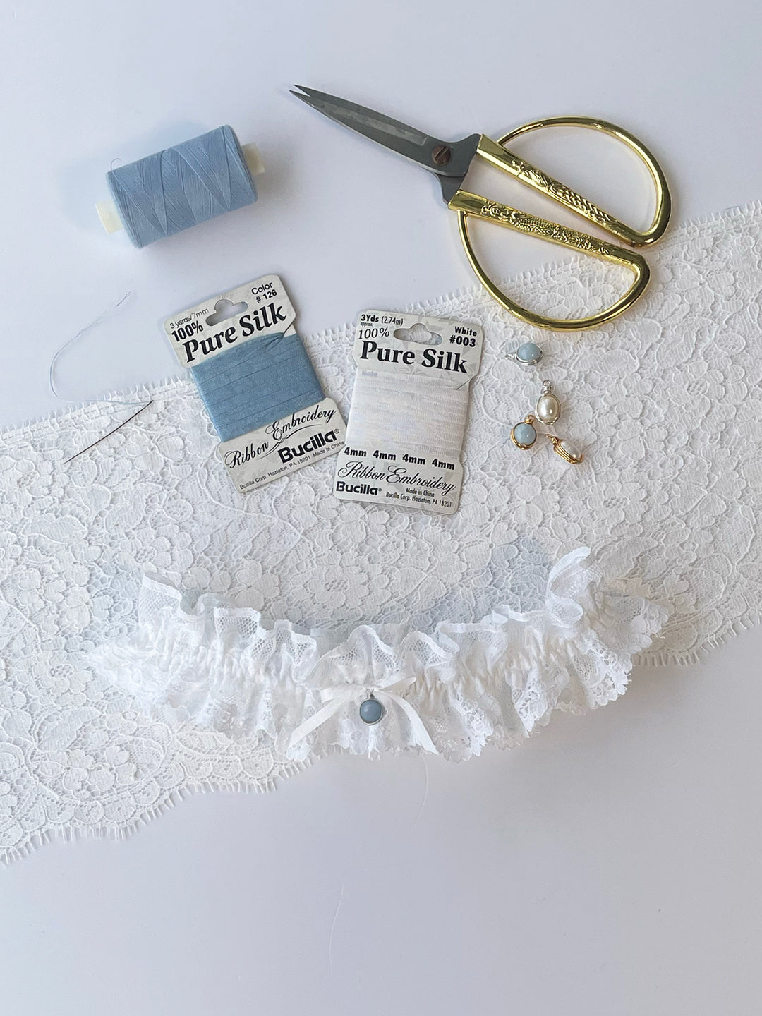 Clara white lace garter with white bow close-up showing handcrafted detail - luxury bridal accessory