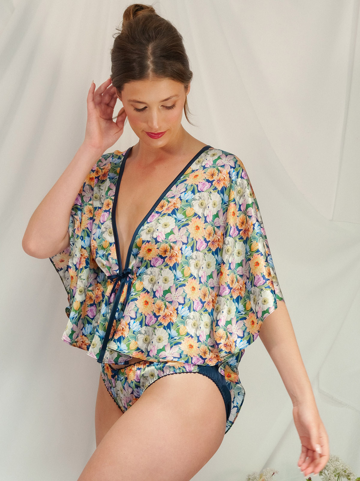 Woman wearing a floral Melody Bloom Liberty Silk Bed Jacket and matching Silk Knicker against a plain background