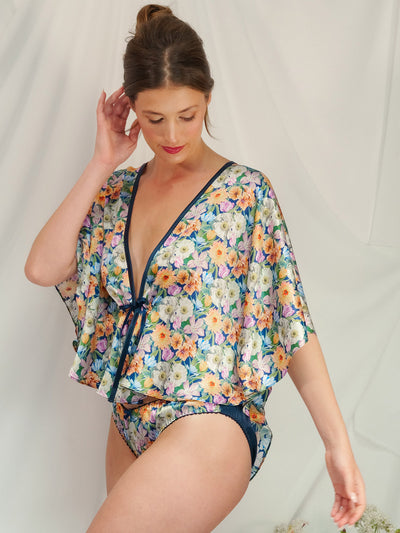 Woman wearing a floral Melody Bloom Liberty Silk Bed Jacket and matching Silk Knicker against a plain background