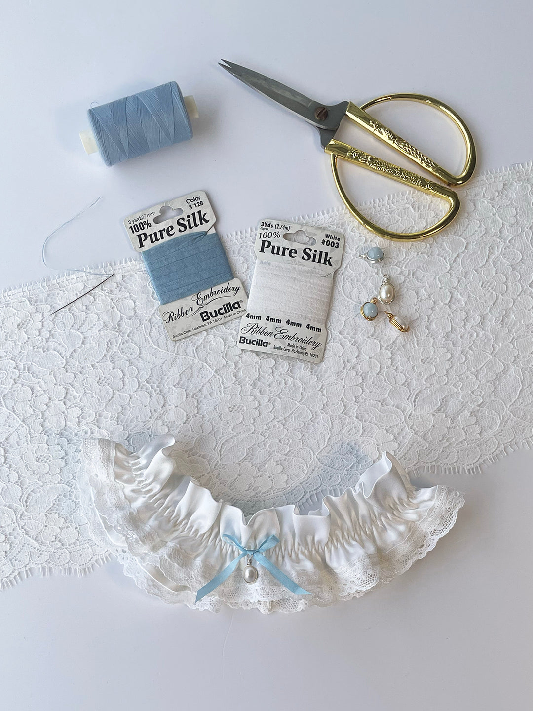 Clara white silk and lace garter with blue bow - handmade bridal lingerie with pearl pendant charm